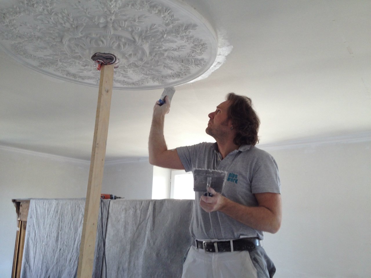 Daniel Stirnimann versetzt eine Stuckrosette an der Decke